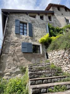 ein Steinhaus mit blauen Fensterläden und Treppen in der Unterkunft Seeblick und offener Kamin - Casa di Florian in Tremosine sul Garda