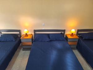 a bedroom with two beds with blue sheets and two lamps at Suítes Recanto Petrópolis in Petrópolis +50 photos
