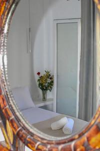 espejo que refleja un dormitorio con cama y flores en Aegean Pearl Studio, en Tinos
