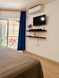 um quarto com uma cama e uma televisão na parede em Studio Apartment Santana Habaneras - 18 at Beach with Garage, Pool and Lift em Torrevieja