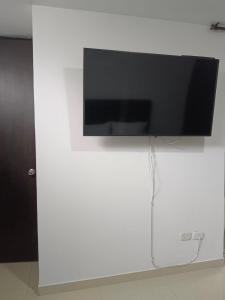 TV de pantalla plana colgada en una pared blanca en Habitación en apartamento familiar, en Armenia