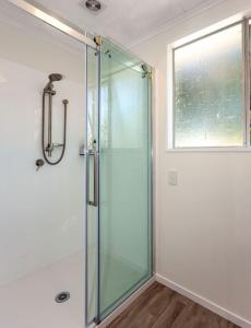 a glass shower in a bathroom with a window at Heart of town in Coromandel Town