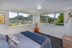 a bedroom with two beds and large windows at Heart of town in Coromandel Town