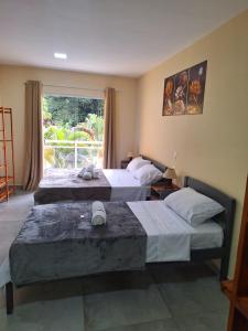 Habitación de hotel con 2 camas y ventana en Suítes Recanto Petrópolis en Petrópolis