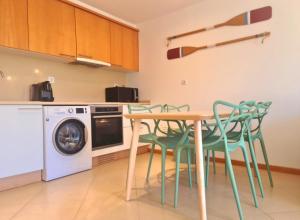 een keuken met een tafel en stoelen en een wasmachine bij Cabanas Garden By HnM in Cabanas de Tavira