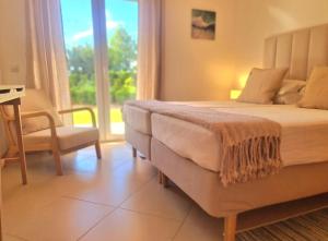 een slaapkamer met een bed, een stoel en een raam bij Cabanas Garden By HnM in Cabanas de Tavira +14 foto's