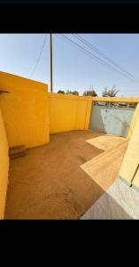 an empty room with a yellow wall and a ramp at Sanyiri meublée in Ouagadougou