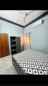 um quarto com uma cama, uma cómoda e uma janela em Sanyiri meublée em Ouagadougou