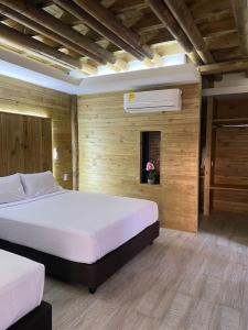 a bedroom with two beds and a air conditioner on the wall at Hotel Explore Caño Dulce in Tubará