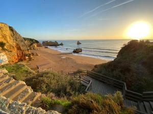 einen Sandstrand mit einer Treppe zum Meer in der Unterkunft Lush Botanic Oasis with a Boho Hideaway, Near Beach & Cafés in Lagos