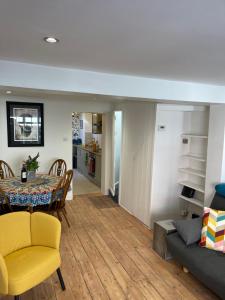 sala de estar y comedor con mesa y sillas amarillas en North Laine Sunny Cottage en Brighton & Hove