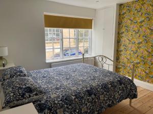 a bedroom with a bed with a blue blanket and a window at North Laine Sunny Cottage in Brighton & Hove