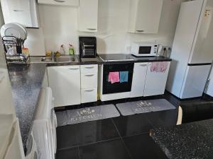 una pequeña cocina con armarios blancos y microondas en Available rooms at Buckingham road en Doncaster