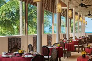 un comedor con mesas, sillas y palmeras en The Ritz-Carlton, Koh Samui, en Choeng Mon Beach