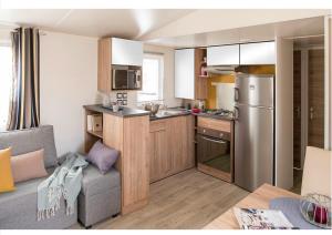 a kitchen with a stainless steel refrigerator and a couch at mobilhome 6/8 personnes in La Tremblade +9 photos