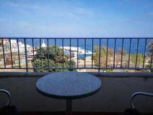 a table on a balcony with a view of the ocean at Hotel Euro Moniz in Porto Moniz