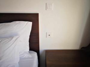 a bed with white sheets and a wooden head board at Hotel Euro Moniz in Porto Moniz