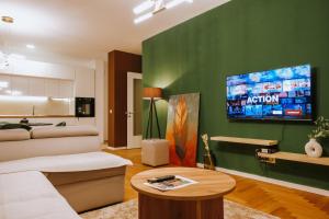a living room with a couch and a tv on a green wall at Lux Nest Apartment Prishtina in Pristina