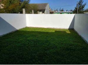 une clôture blanche avec un champ vert d'herbe dans l'établissement Casa em Atlântida Sul, com 2 quartos e 2 banheiros, com ar condicionado., à Xangri-lá