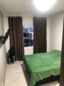 - une chambre avec un lit vert et une fenêtre dans l'établissement Casa em Atlântida Sul, com 2 quartos e 2 banheiros, com ar condicionado., à Xangri-lá