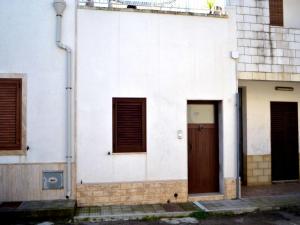 a white building with brown doors and windows at Wabis two-room apartment on the ground floor in San Foca in San Foca