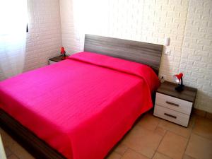 a bedroom with a red bed with a wooden headboard at Wabis two-room apartment on the ground floor in San Foca in San Foca