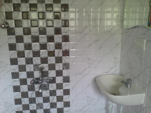 La salle de bains est pourvue d'un lavabo et d'un mur carrelé. dans l'établissement Galaxy Vaibhav, à Vasai