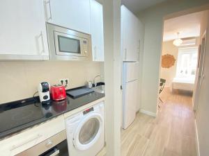 a kitchen with a washing machine and a microwave at ESTUDIOS GRAN VÍA in Madrid