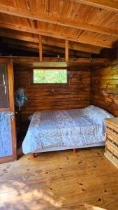 Cabaña Los Cipreses في تيغري: غرفة نوم بسرير في كابينة خشبية