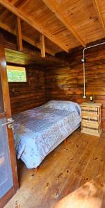 Cabaña Los Cipreses في تيغري: غرفة نوم بسرير في كابينة خشبية