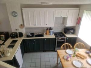 a small kitchen with green cabinets and a table at Cosy Cottage in Saint Columb Major