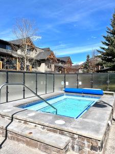 a swimming pool with a fence and a house at Perfect family 2-bed Condo with hot tub in Dead Man's Flats