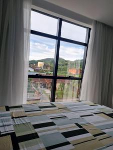 a room with a large window and a bed at Flat Home Business 303 Centro de Pomerode in Pomerode