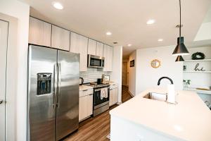 una cocina con nevera de acero inoxidable y armarios blancos en Uptown Fully Furnished 2BR Apartment apts, en Charlotte