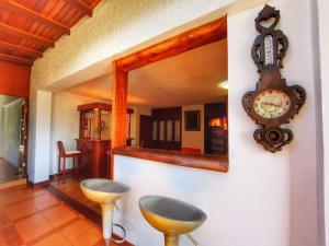 a room with a clock on the wall and two stools at Villa Valcore in Mérida