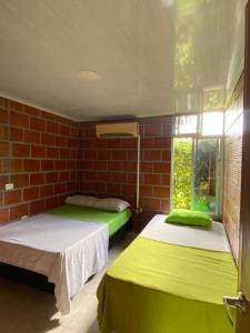 2 camas en una habitación con una pared de ladrillo en ECORAUDAL posada campestre, en San José del Guaviare