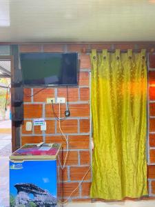a brick wall with a tv and a yellow curtain at ECORAUDAL posada campestre in San José del Guaviare