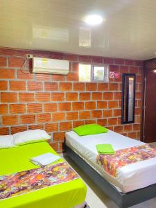 two beds in a room with a brick wall at ECORAUDAL posada campestre in San José del Guaviare