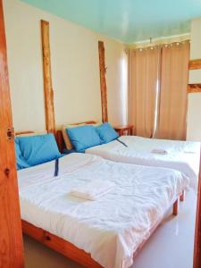 2 łóżka w pokoju z niebieskimi poduszkami w obiekcie Aesthetic Infused with Rustic Vibe Rooms at BOONE'S w mieście Sagada