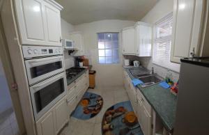 a kitchen with white cabinets and a stove top oven at Gloria's Hideaway in Christ Church