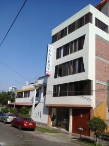 un edificio blanco con un coche rojo estacionado frente a él en HOSPEDAJE VALERY, en Trujillo