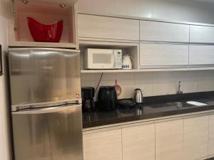 eine Küche mit einem Kühlschrank aus Edelstahl und einer Mikrowelle in der Unterkunft Nautilus Home Club próximo ao Beto Carrero e praias in Penha