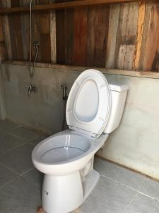 een wit toilet met de bril omhoog in een badkamer bij สวนบ้านนอก in Phayao