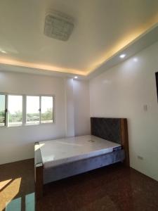 ein Schlafzimmer mit einem Bett in einem Zimmer mit Fenstern in der Unterkunft TERESITA RESIDENCE in Manaoag