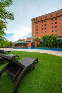 Hotel GH Guaparo INN في Naguanagua: حديقة بها كرسيين أمام المبنى