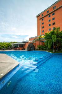 a large blue swimming pool in front of a building at Hotel GH Guaparo INN in Naguanagua