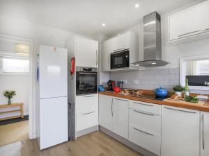 a kitchen with white cabinets and a white refrigerator at Sea Breeze in Wembury