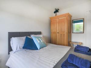 1 dormitorio con 1 cama con almohadas azules y armario de madera en Sea Breeze en Wembury