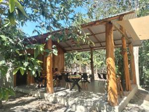 eine hölzerne Pergola mit einem Tisch und Stühlen in der Unterkunft El Gecko Hotel & Tours in Paquera