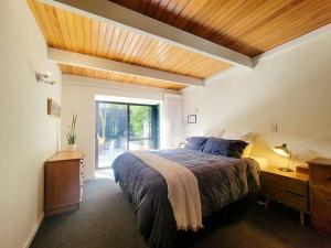 um quarto com uma cama grande e uma janela em Hagley Park Townhouse em Christchurch